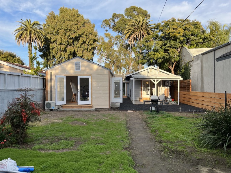 The finished studio and covered patio at the back of the lot, with bare ground still waiting to be planted.