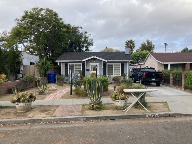 The front yard before the redesign: bare dirt and gravel with a few scattered agaves, potted succulents, and a brick path.