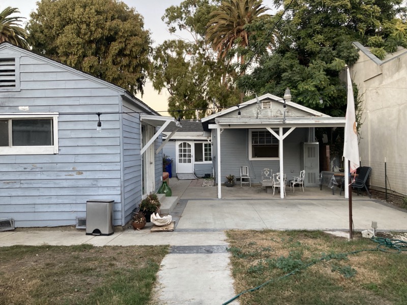The back of the house before work started, with a covered porch and worn patchy lawn.