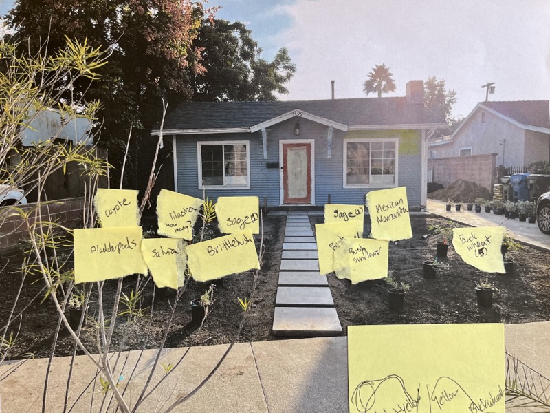 A printed photo of the front yard covered in yellow sticky notes, each naming a plant for that spot.